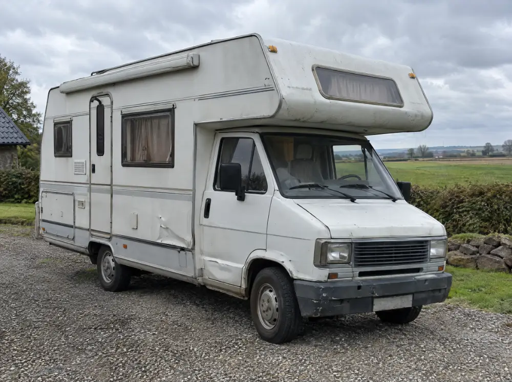 Ældre hvid autocamper på en gruset plads